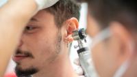 Doctor examining patient's ear with otoscope